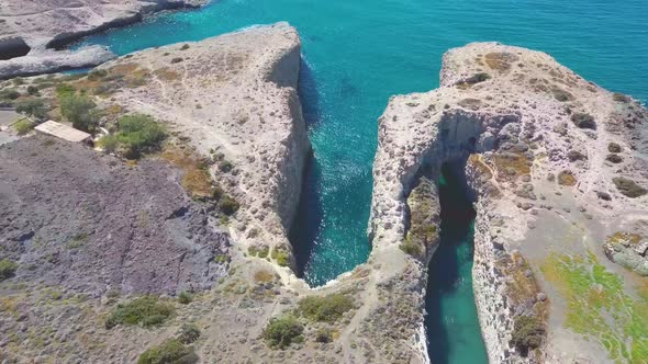 Aerial view to the popular Papafragas cave beach situated in volcaninc landscape with turquoise wate