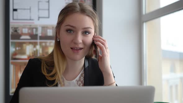 Happy Woman Architect Talking By Mobile Phone at Table in Creative Office