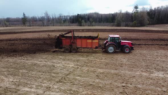 Tractor with Trailer Spreading Organic Manure on Farm Field