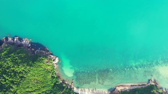 Peaceful bay with turquoise lagoon full of corals, washing sandy beach and rocky coastline of tropic