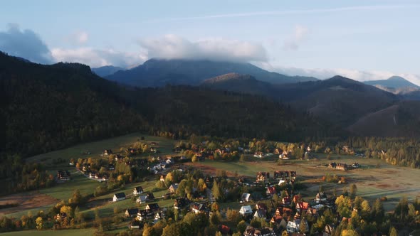 Aerial View Flight Over Mountain Village Lit with Warm Sunlight