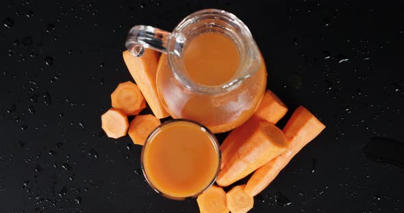 Carrot Juice in Glass and Jug. A Slow Rotation