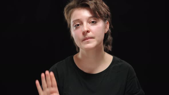 Closeup Portrait of Scared Abused Young Woman Looking Around and Showing Sign to Help Palm at Camera