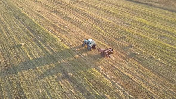 Upper View Tractor Pulls Bale Collector on Harvested Field