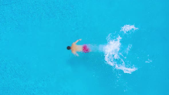 View From the Top As a Man Dives Into the Pool and Swims Under the Water. Slow Motion