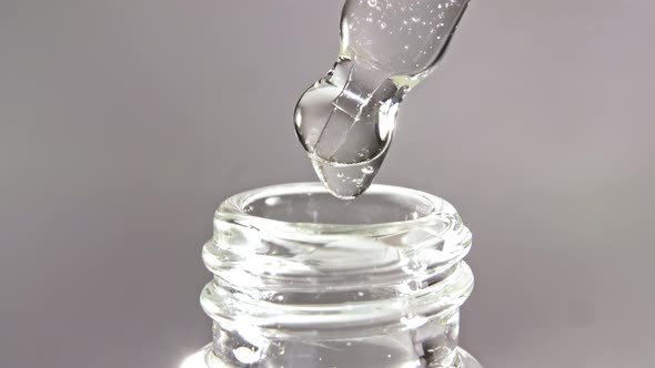 Cosmetic Pipette with Drops of Oil Close Up on Gray Background