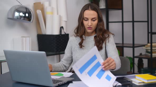 Female Employee Looking Through Workpapers on the Table Trying to Find Needed