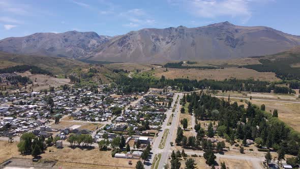 Pan left flying above Esquel village surrounded by trees and Andean mountains, Patagonia Argentina