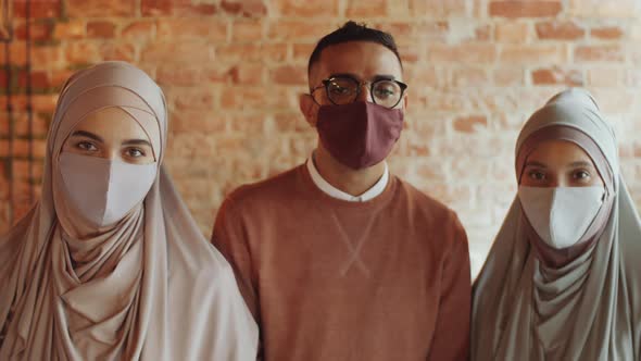 Two Muslim Women and Young Arab Man in Face Masks Posing for Camera