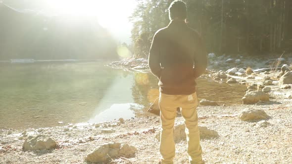Man standing at mountain lake, enjoying view