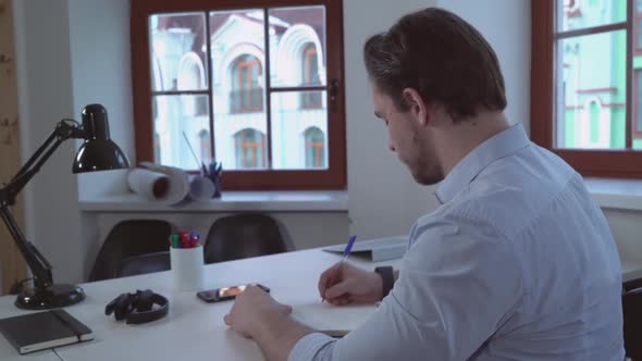 Businessman Writing in Notebook