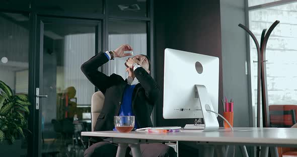 Businessman in Office in Front of Computer Dripping Drops in Eyes