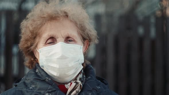 Elderly Woman in a Respirator Protection Mask is Walking the Street