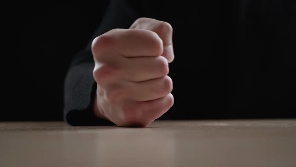 Close Up Man Beats His Fist on the Table Showing Aggression on Dark Background