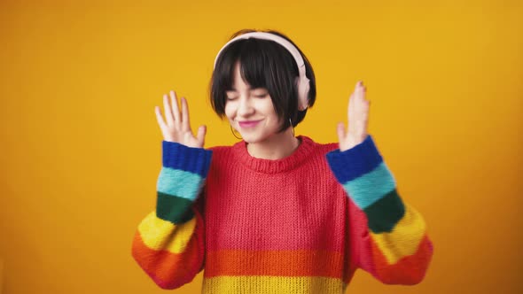 Studio Shot of Young Active Woman Listening to Music in Wireless Headphones and Dancing Enjoying