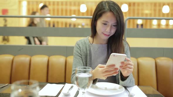 Woman working on mobile phone in restaurant