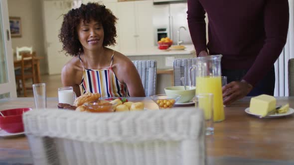 African american family having breakfast sitting together on dining table at home