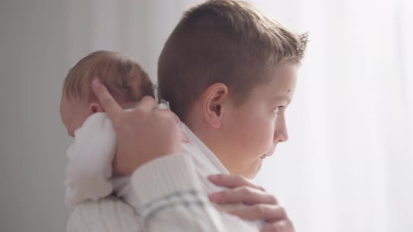 Closeup Portrait Loving Brother Hugging Shaking Calming Down Baby Sister in Slow Motion