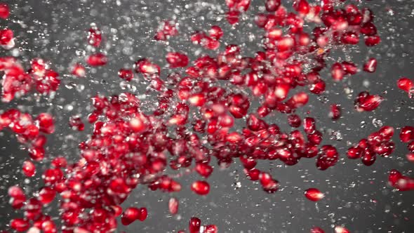 Super Slow Motion Shot of Fresh Pomegranate Seeds and Water Side Collision on Grey at 1000Fps