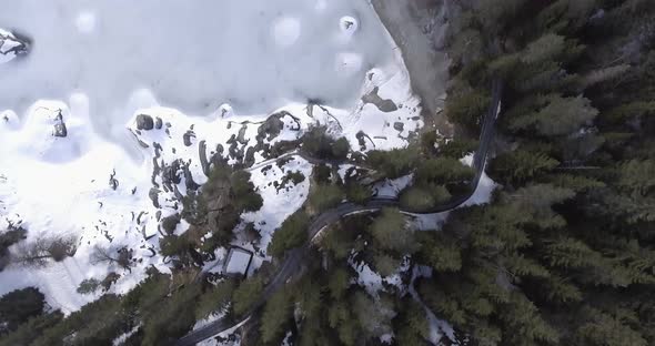 Flight over a road surrounded by trees and a lake.