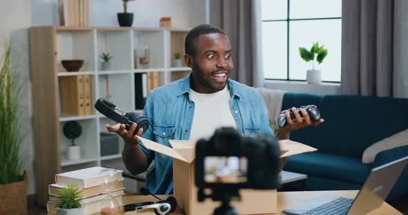 African American Blogger Showing Purchases from Carton on Camera while Recording New Video