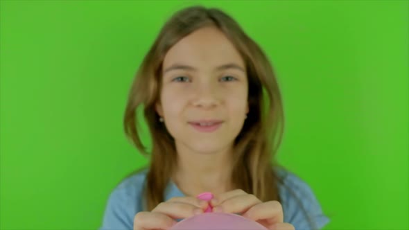 A Child Blows a Balloon on a Green Background