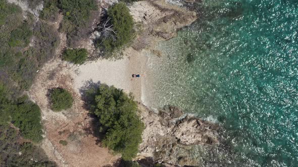 Aerial View of a Woman in a Bathing Suit Lying on the Beach By the Sea