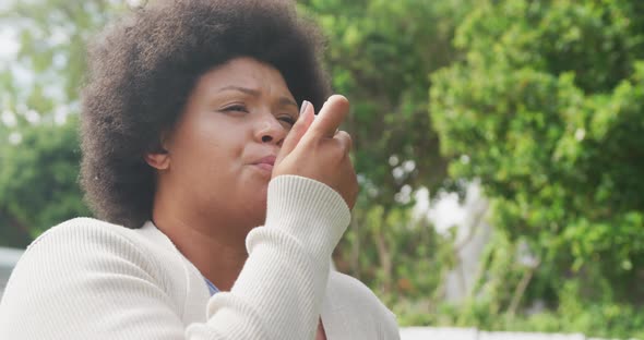 Video of plus size african american woman using inhalator outdoors