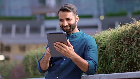 Smiling Indian Professional Business Man Using Digital Tablet in City Park