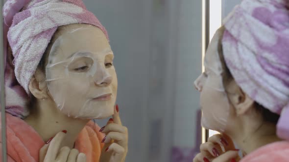 Woman Applying Cosmetic Face Mask in Bathroom. Skincare Spa. Facial Mask