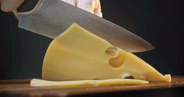 Person Cuts Expensive Cheese with Holes on Wooden Board