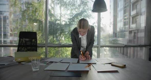Young Busy Blond Business Woman Working on Project Paperwork Talking on the Phone