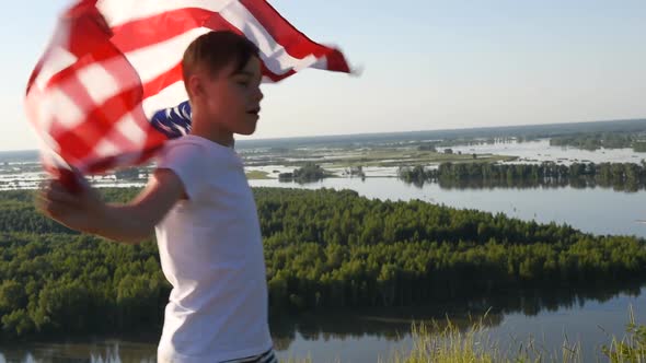 Blonde Boy Waving National USA Flag Outdoors Over Blue Sky at the River Bank