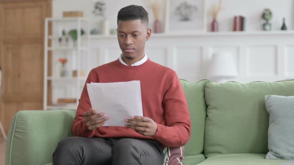 African Man Reading Documents on Sofa