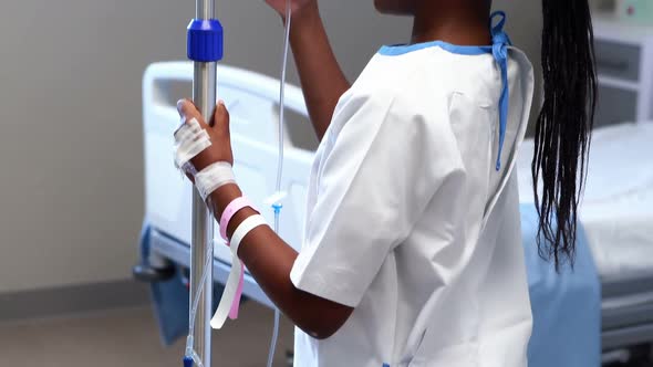 Portrait of sick girl holding iv drip stand