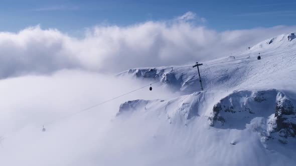 Aerial view over gondola on the cliff with snowy mountain ridge valley with in winter