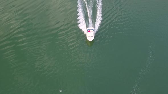 Athletic young man wakeboarding when a boat is pulling him speed. Doing tricks, jumps and curves. Ae