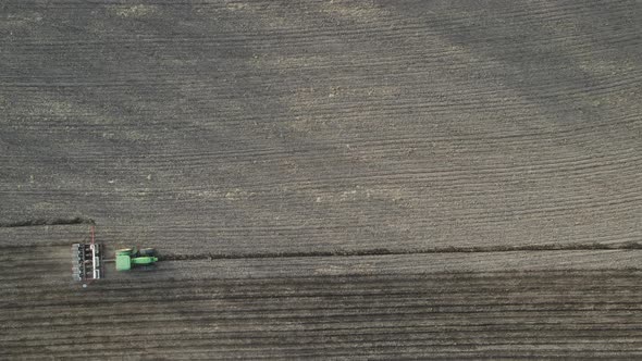 Top down view of empty farm field being fertilized and seeded. Dust from dry dirt being stirred.