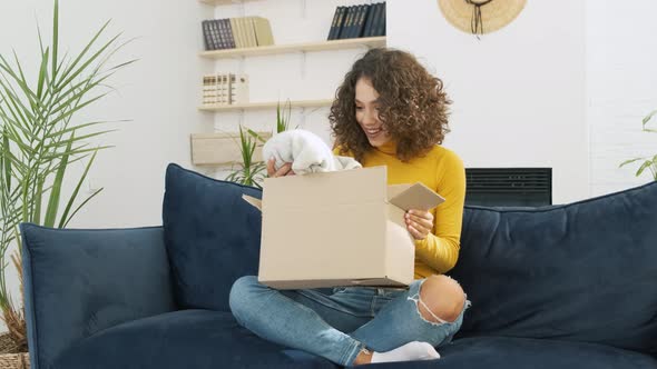 Excited Young Woman Unpacking Huge Carton Box Looking Inside