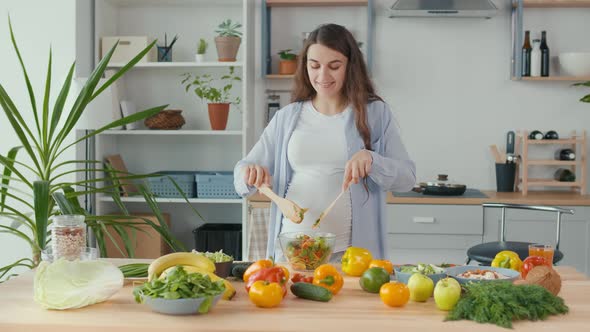 Happy Pregnant Woman Preparing Organic Healthy Food aWoman Mixes Vegetable Salad