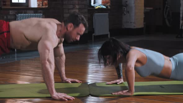 Couple in the Gym  Doing Push Ups Together on Yoga Mats and Doing a Clap to Each Other