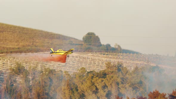 Fire fighter plane drops fire retardant on a forest fire in the hills