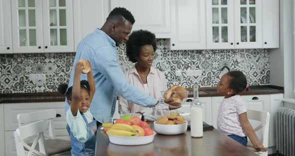 African American Family which Have Breakfast with Freshly Baked Rolls in Contemporary Kitchen