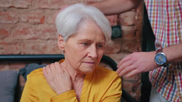 Portrait of Worried Elderly Woman Sadly Gazing Into the Eyes of Her Middleaged Grandchild Supporting