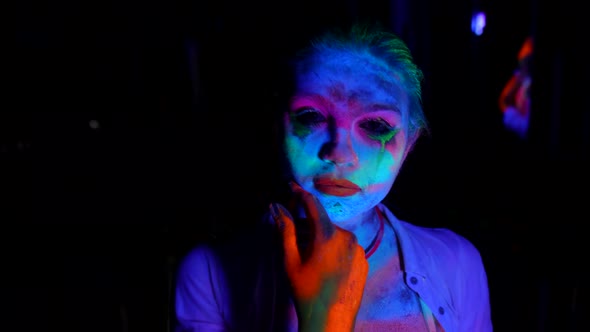 Young Actress with Fluorescent Makeup Medium Portrait in UV Lights in Darkness