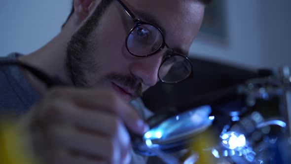 Portrait of Successful Young Bearded Man in Glasses Working with a Soldering Iron at His Working