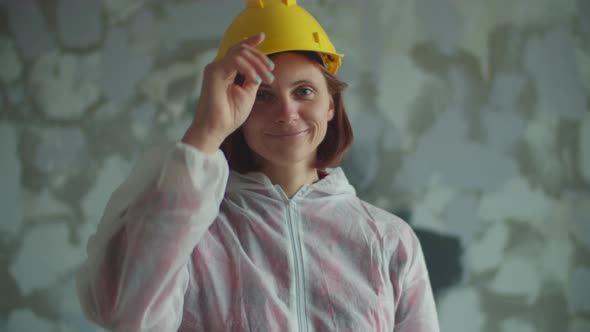 Young 30s Female Painter Putting on Yellow Hardhat and Yellow Protective Glasses Looking at Camera