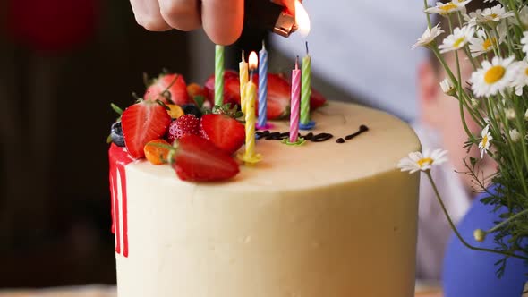 hand lighting candles in birthday cake.