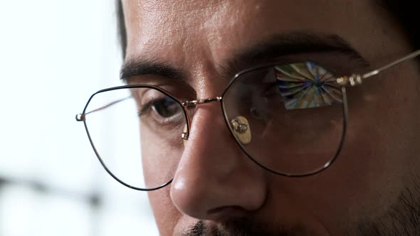 Close-up Portrait of a Young European Man with Glasses, the Reflection of Images is Working 