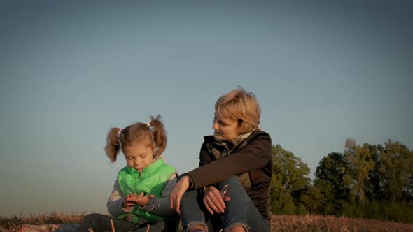 Woman with Little Daughter Sitting During Amazing Sunset